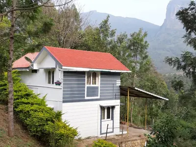a small white house with a red roof at jacaranda resorts in Kanthalloor