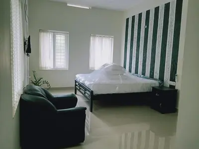 a bedroom with a bed and a chair at Village of Blossom in Ernakulam