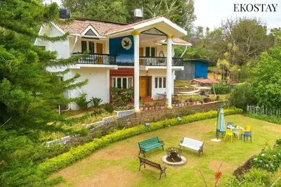 a house with a yard with benches and tables at EKOSTAY - Moonlight Villa in Kodaikānāl