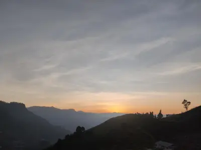 a sunset in the mountains with a palm tree on a hill at Divercity Luxury Glamp in Kodaikānāl