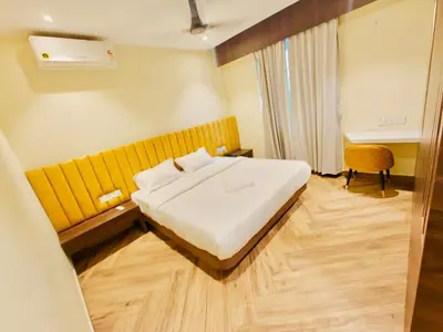 a hotel room with a bed and a yellow wall at S K Legacy Hotel in Mysore
