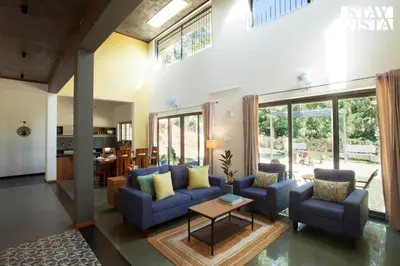 a living room with blue couches and a table at StayVista at The Big Chill with Breakfast Included in Wayanad