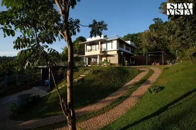 a house on a hill with a tree in front of it at StayVista at The Big Chill with Breakfast Included in Wayanad