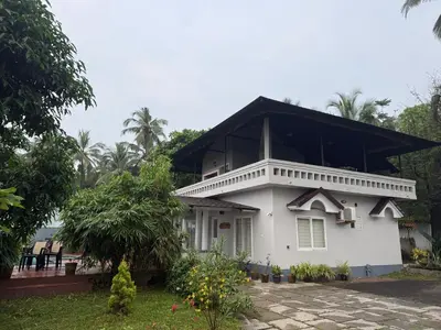 a white house with a black roof at Kappad Beach House by Kisah Stays in Kappad