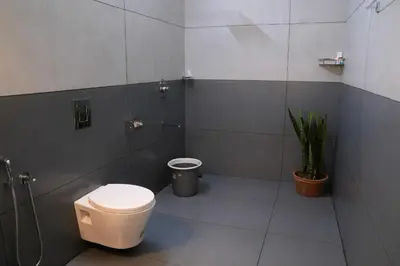 a bathroom with a toilet and a potted plant at Kappad Beach House by Kisah Stays in Kappad