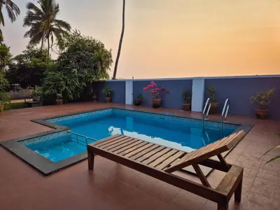a swimming pool with a bench and a chair next to it at Kappad Beach House by Kisah Stays in Kappad