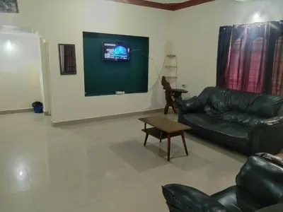 a living room with a leather couch and a tv at Samz estate stay 2BHK in Madikeri