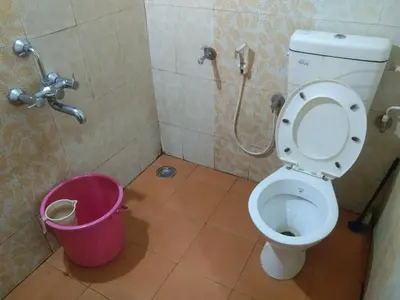 a bathroom with a toilet and a pink bucket at Samz estate stay 2BHK in Madikeri