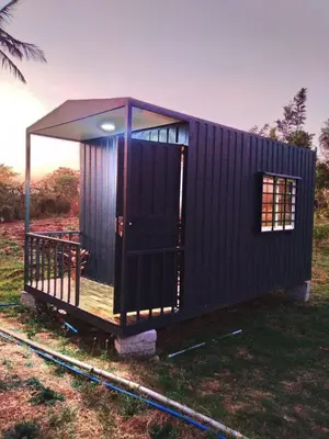 a black tiny house with a porch on the grass at Golden Triangle River side Cabin in Mysore