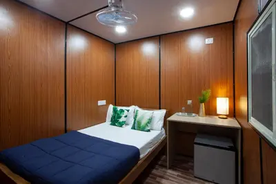 a small room with a bed and a desk at Golden Triangle River side Cabin in Mysore