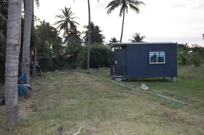 a person sitting in a hammock next to a tiny house at Golden Triangle River side Cabin in Mysore