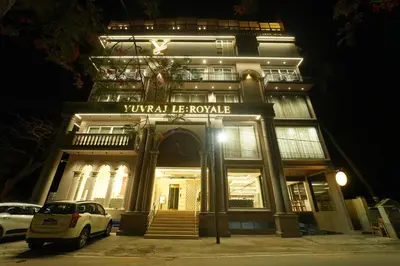 a white car parked in front of a building at night at Yuvraj Le: Royale in Mysore