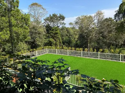 a garden with a white fence and green grass at Coorg Le Embera in Virajpet