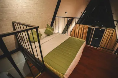a swing bed in a room with two windows at Inika in Ponnampet