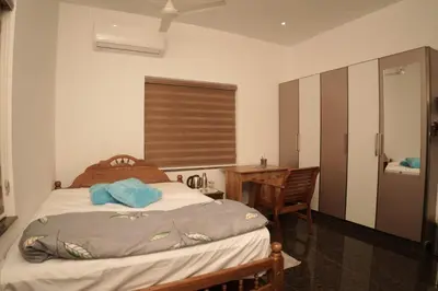 a bedroom with a bed and a desk and a table at Happy Villa Homestay in Chelakara