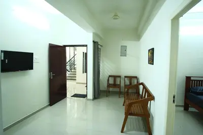 a living room with a couch and a tv on a wall at Greens in Kozhikode