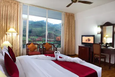 a hotel room with a bed and a desk and a window at Hotel C7 Munnar in Munnar