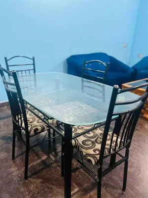 a glass table with two chairs and a blue couch at Dreamy bungalow 2BHK apartment in Mysore