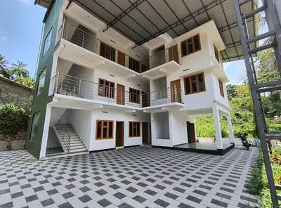 a large white building with balconies and a courtyard at GREEN FIELDS Apartments in Mananthavady