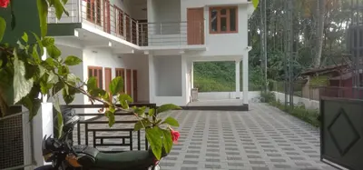 a house with a scooter parked in front of it at GREEN FIELDS Apartments in Mananthavady