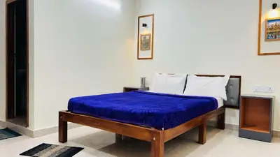 a bedroom with a bed with a blue blanket on it at Hidden doors in Ooty