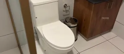 a white toilet in a bathroom with a trash can at Thanima Farmlife experiential Farm Tourism in Nallepilli