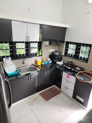 a kitchen with black and white cabinets and a sink at Olive Home stay Gold 1bhk in Alwaye