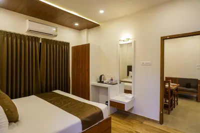 a bedroom with a bed and a desk and a mirror at Grand Plaza Inn in Kottakkal
