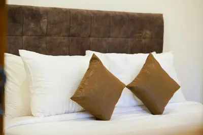 a bed with white pillows and a brown headboard at Grand Plaza Inn in Kottakkal