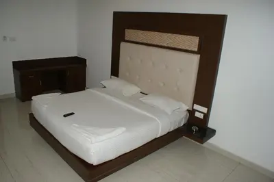 a bed with a wooden frame and white sheets at Sri Ranga Nivas in Palani