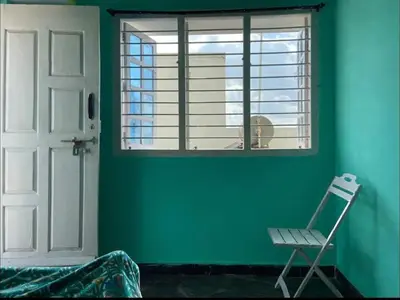 a green room with a chair and a window at Roof top couple stay cozy in Mysore