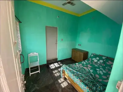 a bedroom with blue walls and a bed and a chair at Roof top couple stay cozy in Mysore