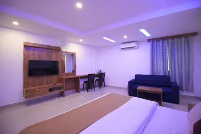 a bedroom with a bed and a tv and a couch at Queen C Inn Wayanad in Mānantoddy