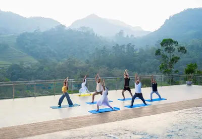 a group of people doing yoga on a boardwalk at The Grand Cliff Resort Munnar in Viripara