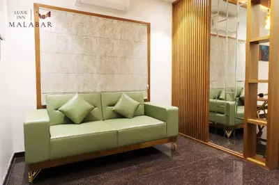 a living room with a green couch and chairs at LUXIE INN MALABAR in Perintalmanna