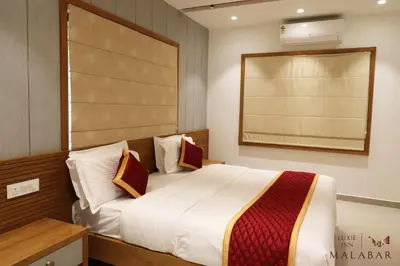 a bedroom with a large white bed with pillows at LUXIE INN MALABAR in Perintalmanna