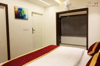 a bedroom with a bed and a window and a door at LUXIE INN MALABAR in Perintalmanna