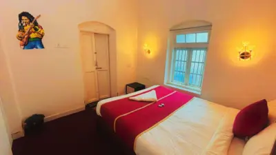 a bedroom with a red and white bed and a window at Hidden heritage ins in Ooty