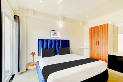 a bedroom with a large bed with a blue curtain at Super Townhouse Mysore Central in Mysore