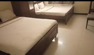 a bedroom with two beds and a chair in it at Renu Residency near Maruthamalai and on the way to Adiyogi Isha yoga Centre in Marudhamalai