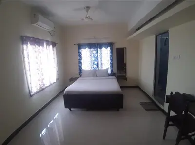 a bedroom with a bed and two windows at Renu Residency near Maruthamalai and on the way to Adiyogi Isha yoga Centre in Marudhamalai