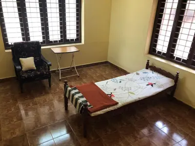 a bedroom with a bed and a chair and a table at Angel Valley in Trichūr