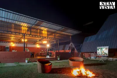 a fire pit in front of a building at night at Golden Apex by VEO - Part of StayVista in Hampāpura