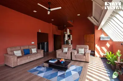 a living room with two couches and a table at Golden Apex by VEO - Part of StayVista in Hampāpura