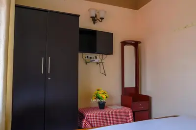 a bedroom with a black cabinet with a tv on the wall at Vijaya Deepa Guest House by LexStays in Coonoor