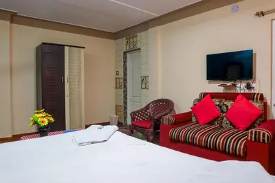 a hotel room with a bed and a couch at Vijaya Deepa Guest House by LexStays in Coonoor