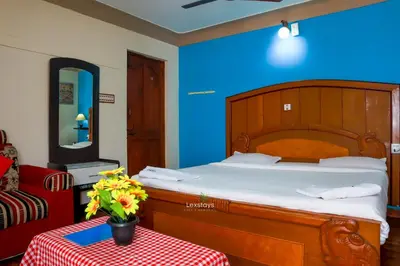 a bedroom with a large bed with a blue wall at Vijaya Deepa Guest House by LexStays in Coonoor