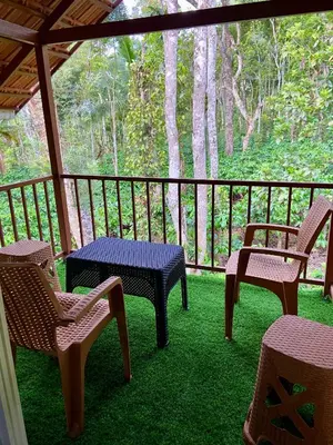 a porch with chairs and tables on the grass at Coorg klusters estate stay in Virajpet