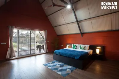 a bedroom with a bed and a large window at Golden Triangle by VEO - Part of StayVista in Hampāpura