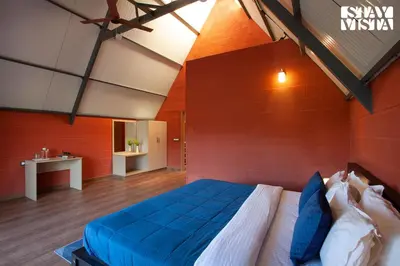 a bedroom with a large bed with a red wall at Golden Triangle by VEO - Part of StayVista in Hampāpura